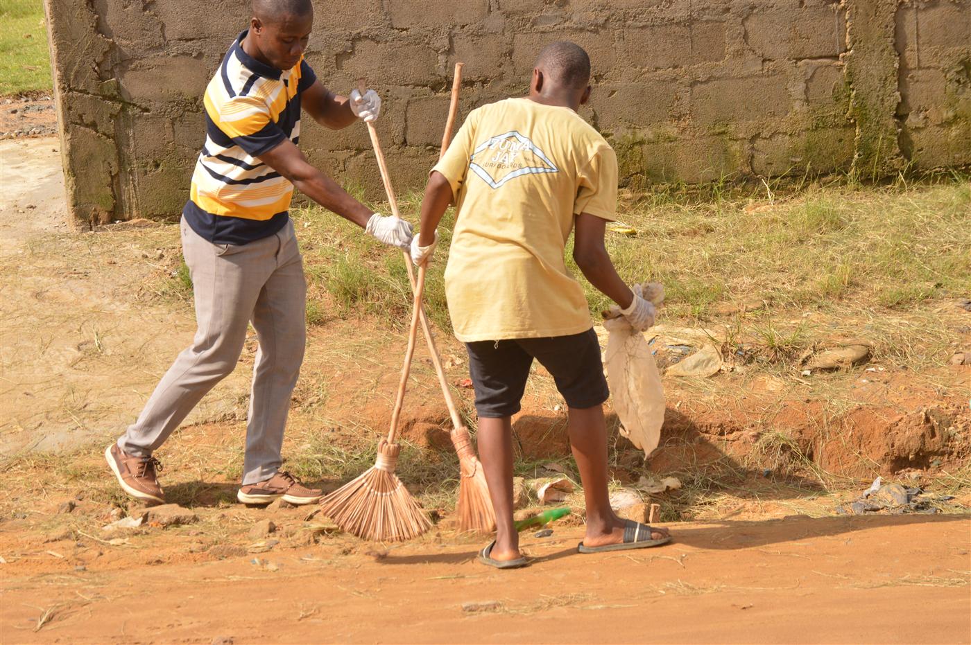 Participants using brooms and waste bags to clean public areas in Soul Clinic.