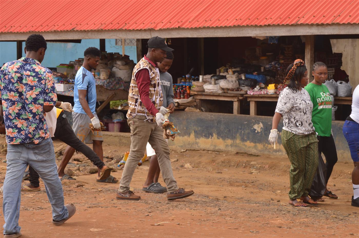Volunteers walking through the community while collecting waste.