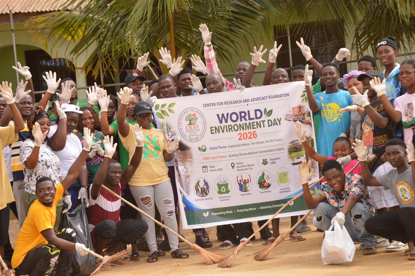 Group photo of volunteers and community participants with the World Environment Day banner.
